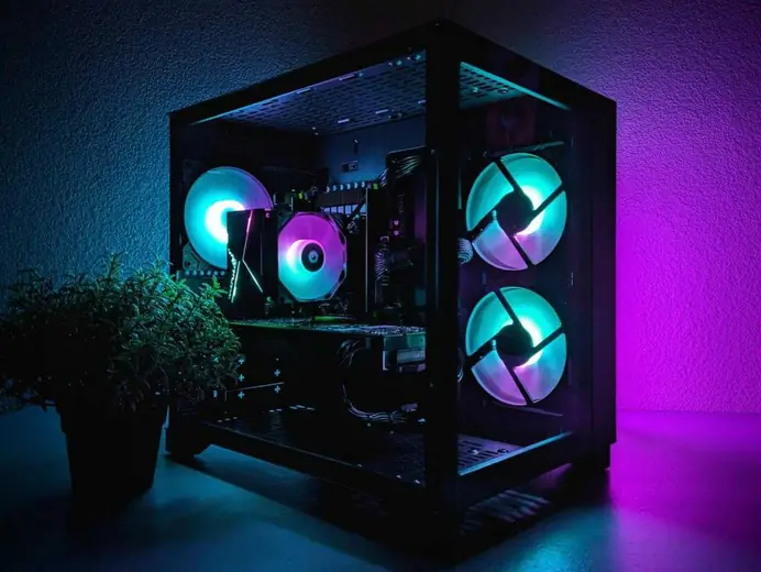 PC vitré aux ventilateurs turquoise et rose dans la pénombre