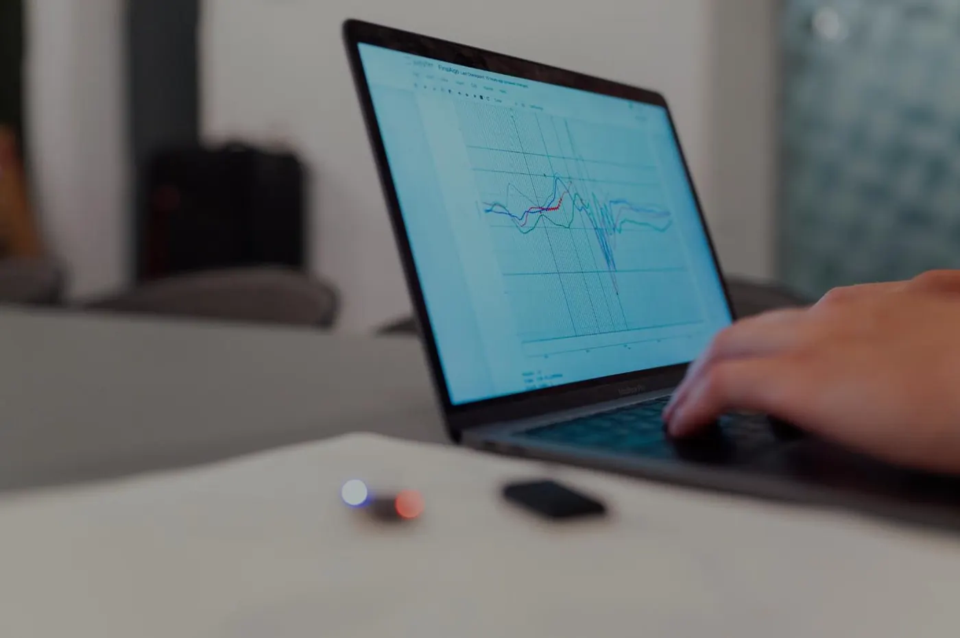 Mains sur le clavier d’un ordinateur portable affichant des courbes de diagnostic