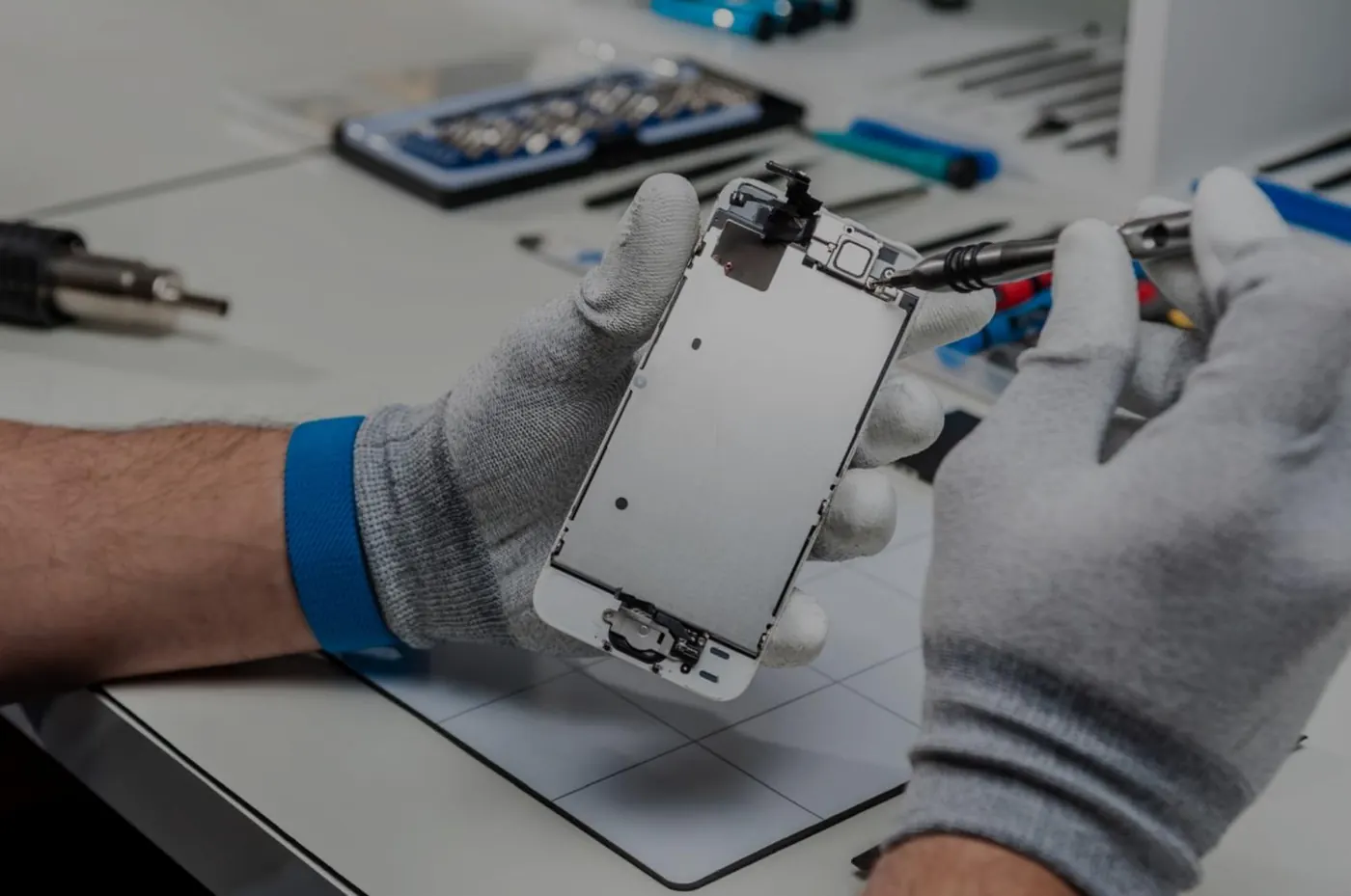Technicien ganté démontant l’écran d’un smartphone à l’atelier
